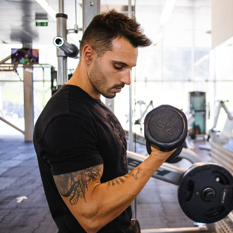 Man exercising with dumbbells in a gym setting